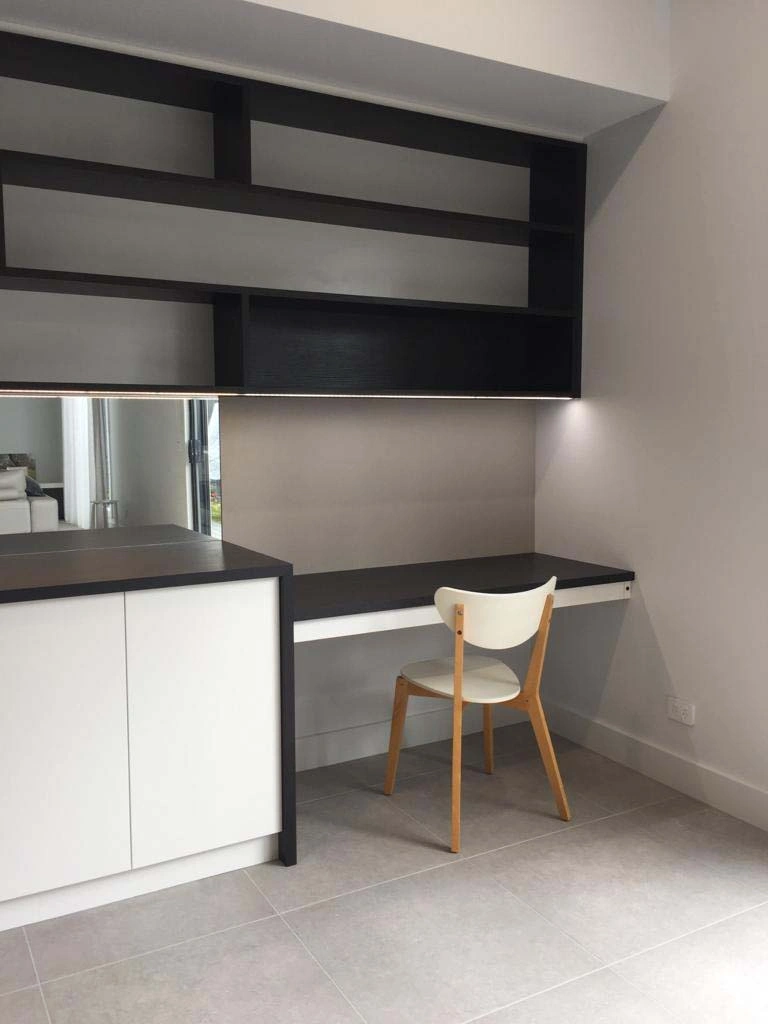 A stylish black and white kitchen that includes a desk and chair