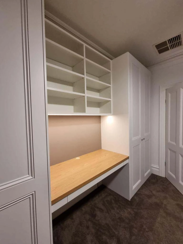 A modern white closet with an integrated desk and shelves