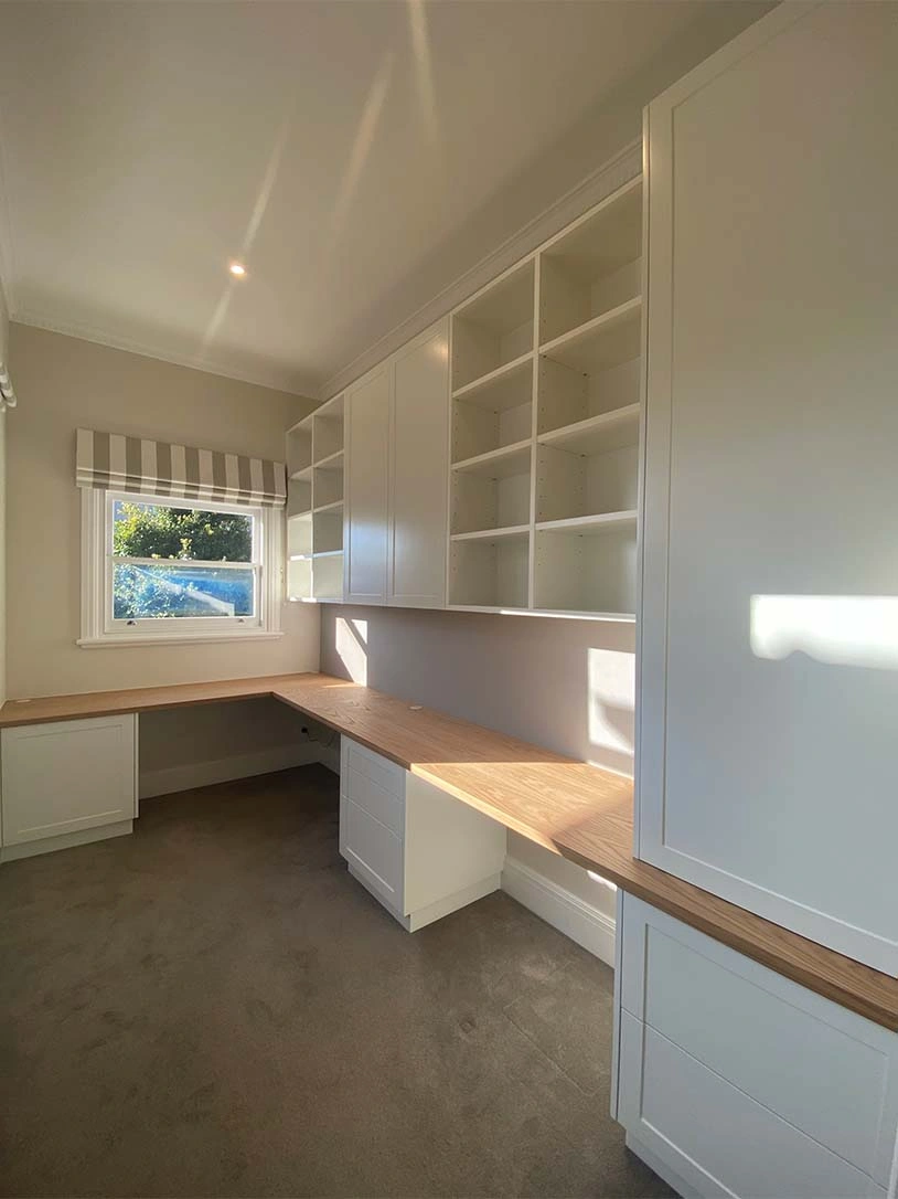 A modern white office space showcasing a tidy desk and storage cabinets