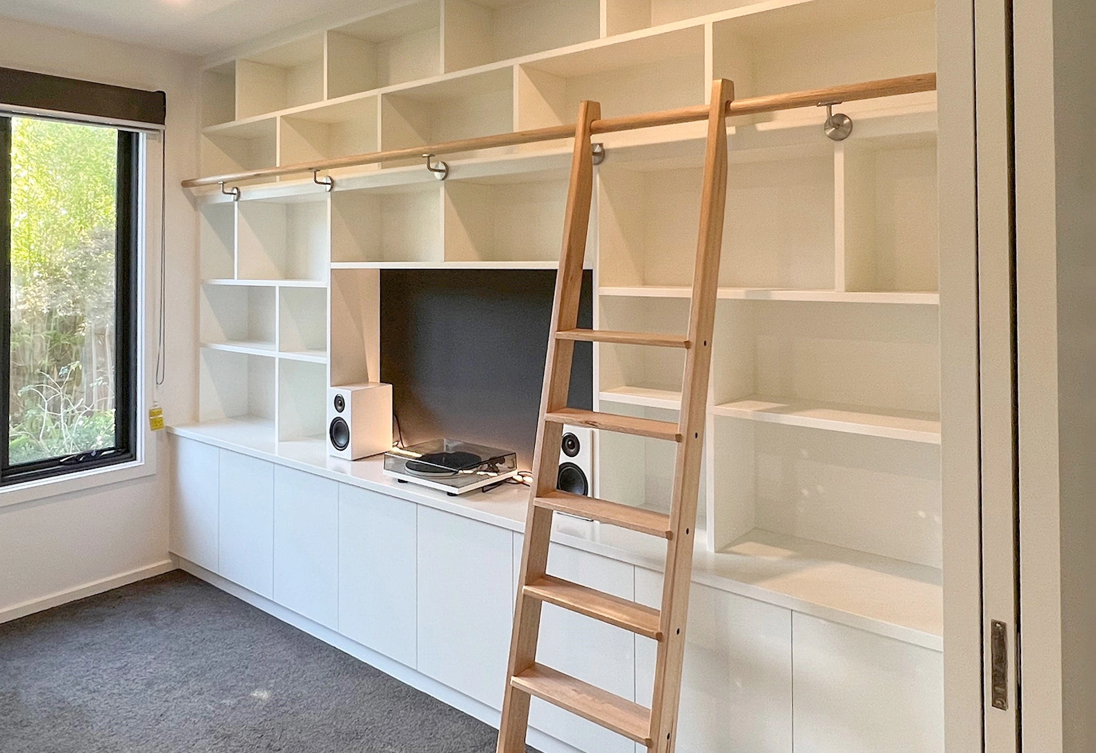 A white bookcase with a ladder in front, illustrating a functional and stylish home office environment