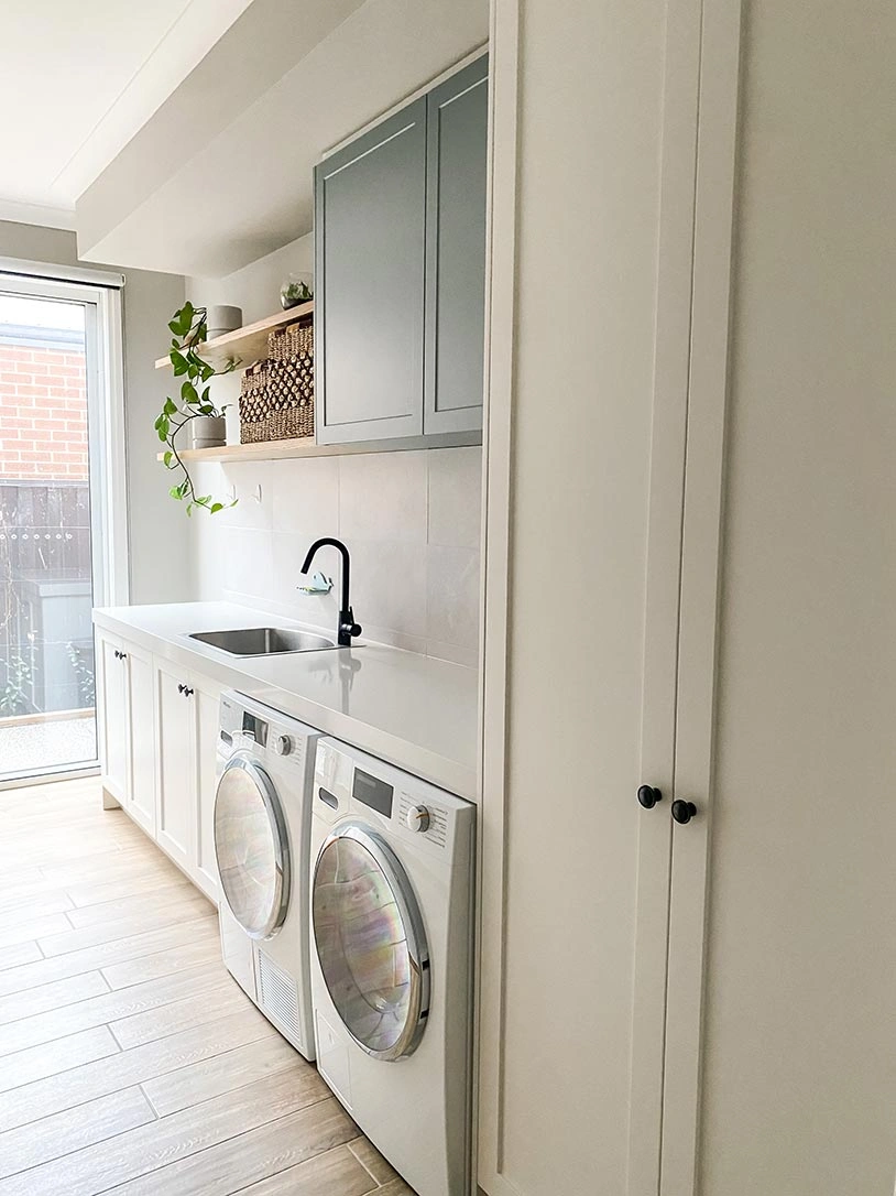 Clean laundry room featuring a modern washer and dryer, with bright lighting and organized shelves in the background