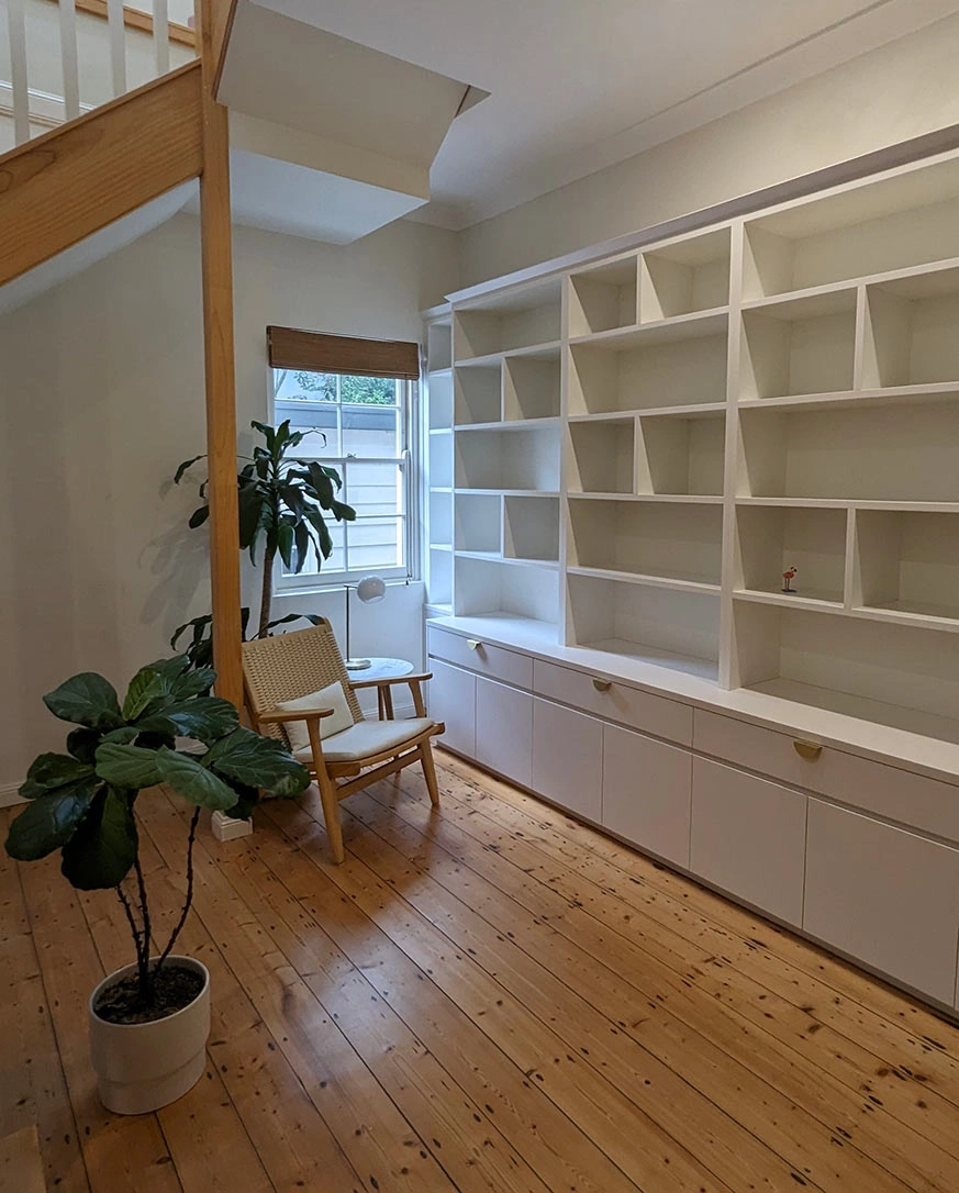 A clean, organized room with white shelves and a single chair, offering a tranquil environment for work or relaxation