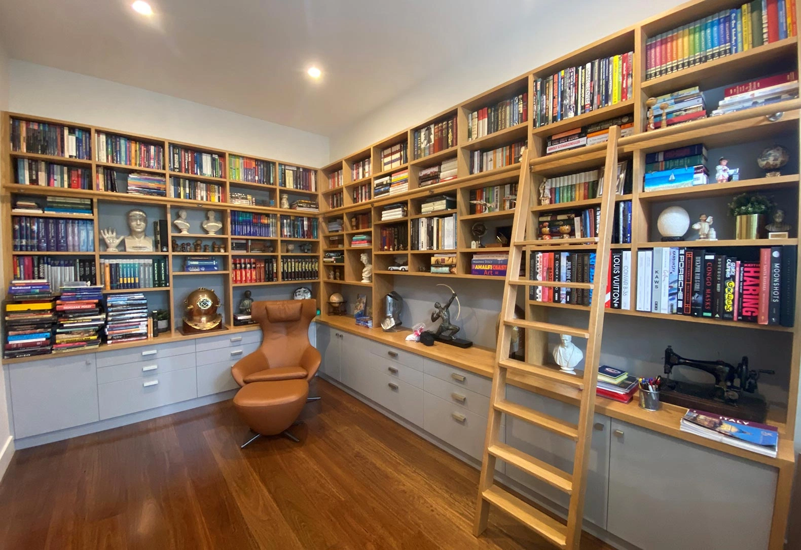 A neat home office with organized bookshelves and a plush chair