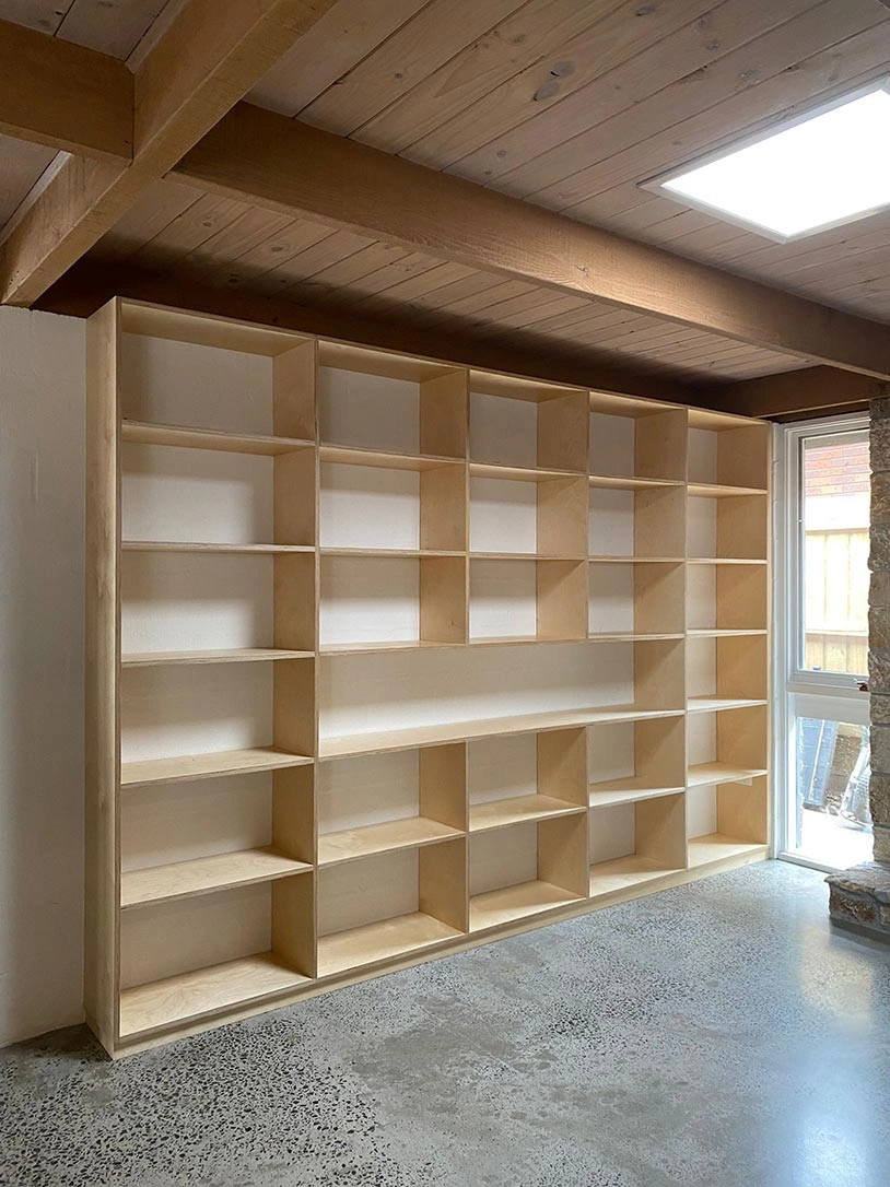 A well-lit room with a big bookcase overflowing with books and a window that brightens the space