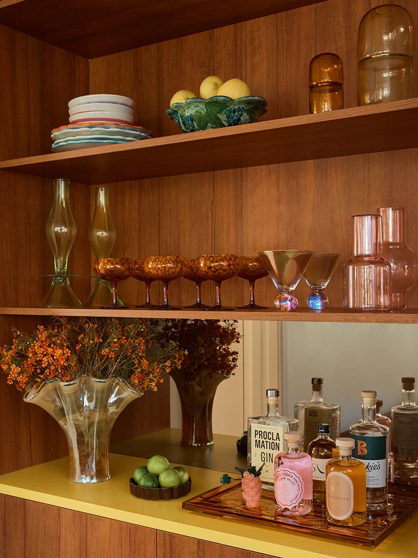 A neatly arranged shelf filled with different styles of glasses and bottles