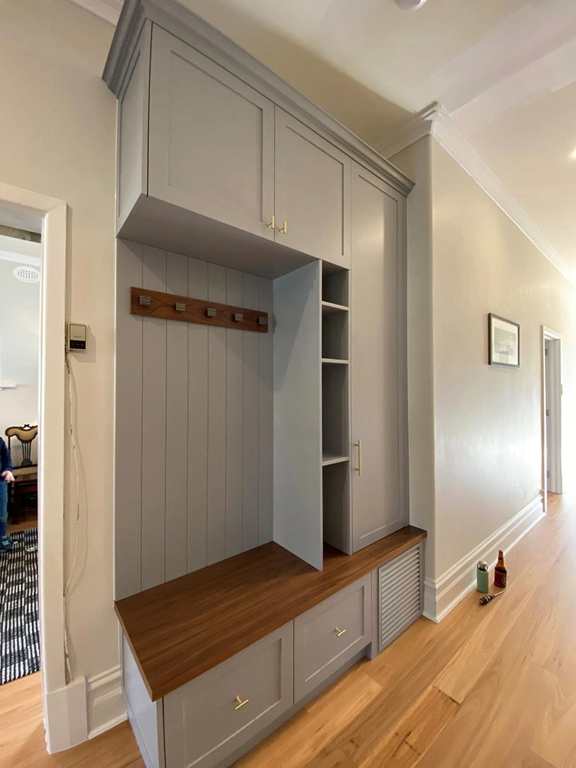 A bright hallway with a smooth wooden floor and minimalist gray cabinets, offering a clean and organized look