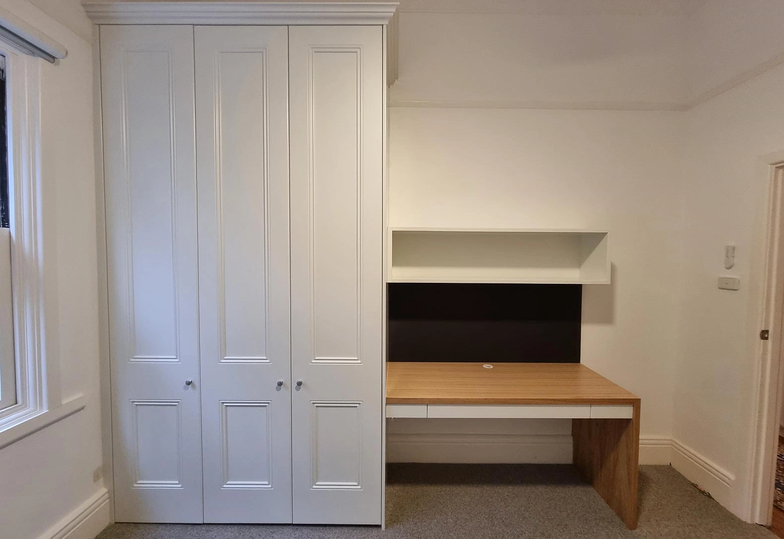 White bedroom with a desk and cupboards