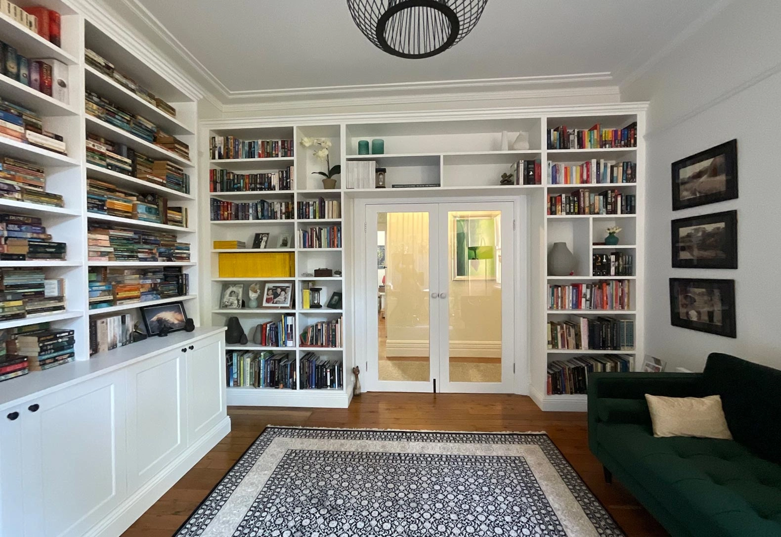 Stylish room that includes a couch, numerous bookshelves, and a door that connects to another area