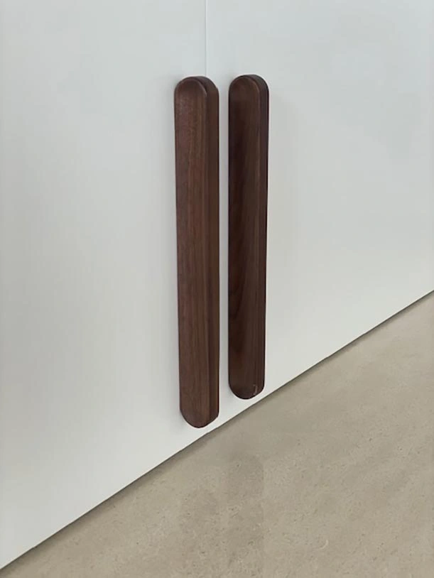 Two wooden handles mounted on a clean white wall