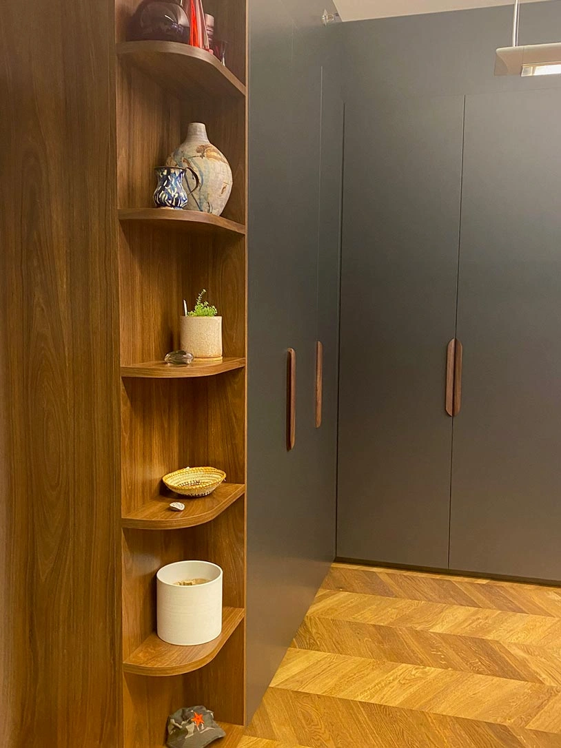 A well-organized room with a wooden shelf displaying items and a cupboard providing additional storage space