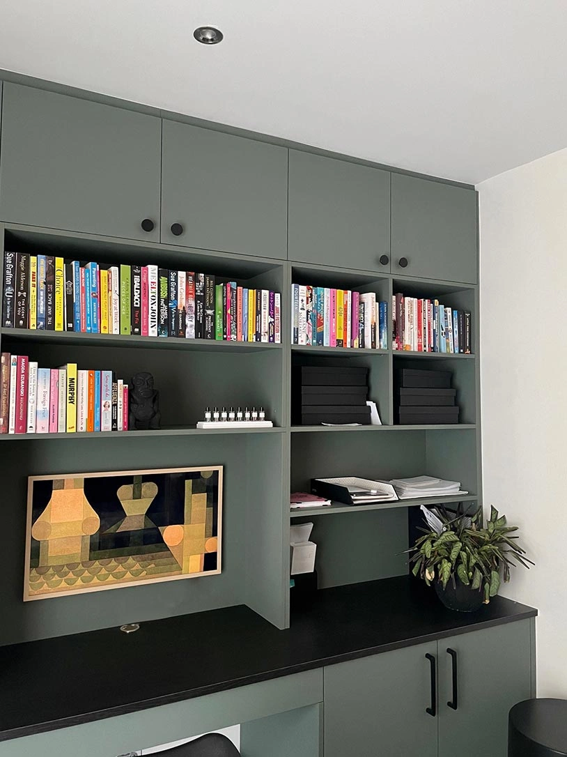 A cozy home office featuring a wooden desk and neatly arranged bookshelves filled with books and decorative items