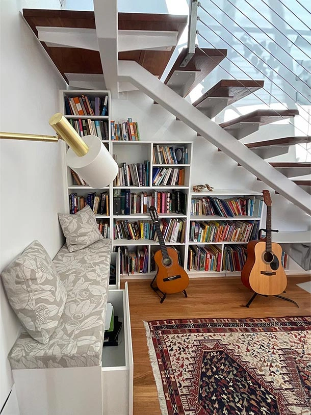 An inviting space with a guitar resting nearby, books neatly arranged, and a soft couch for a comfortable reading nook