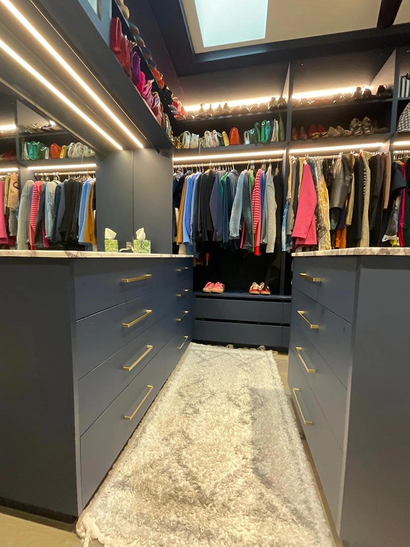 Spacious walk-in closet featuring blue cabinets and a large mirror