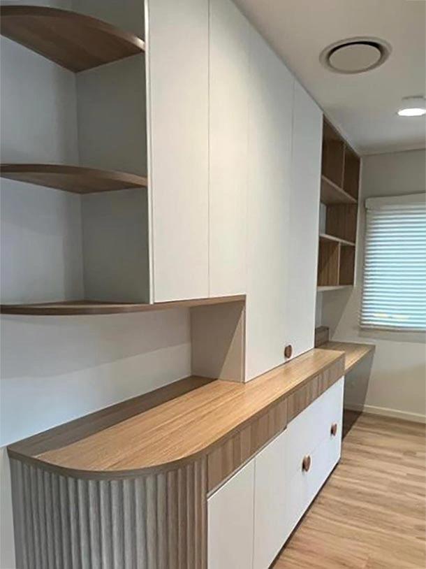 A well-organized room featuring a desk and shelves, creating a functional and inviting workspace atmosphere