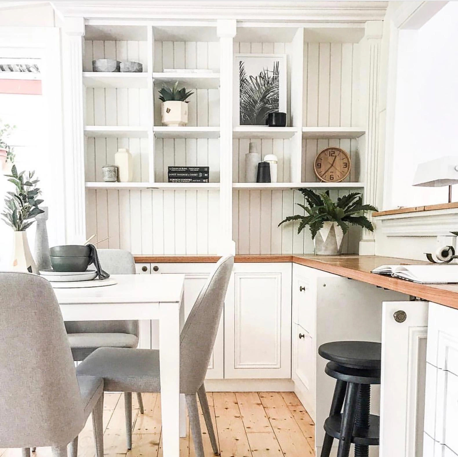 A spacious white kitchen with elegant wooden flooring and pristine white cabinets