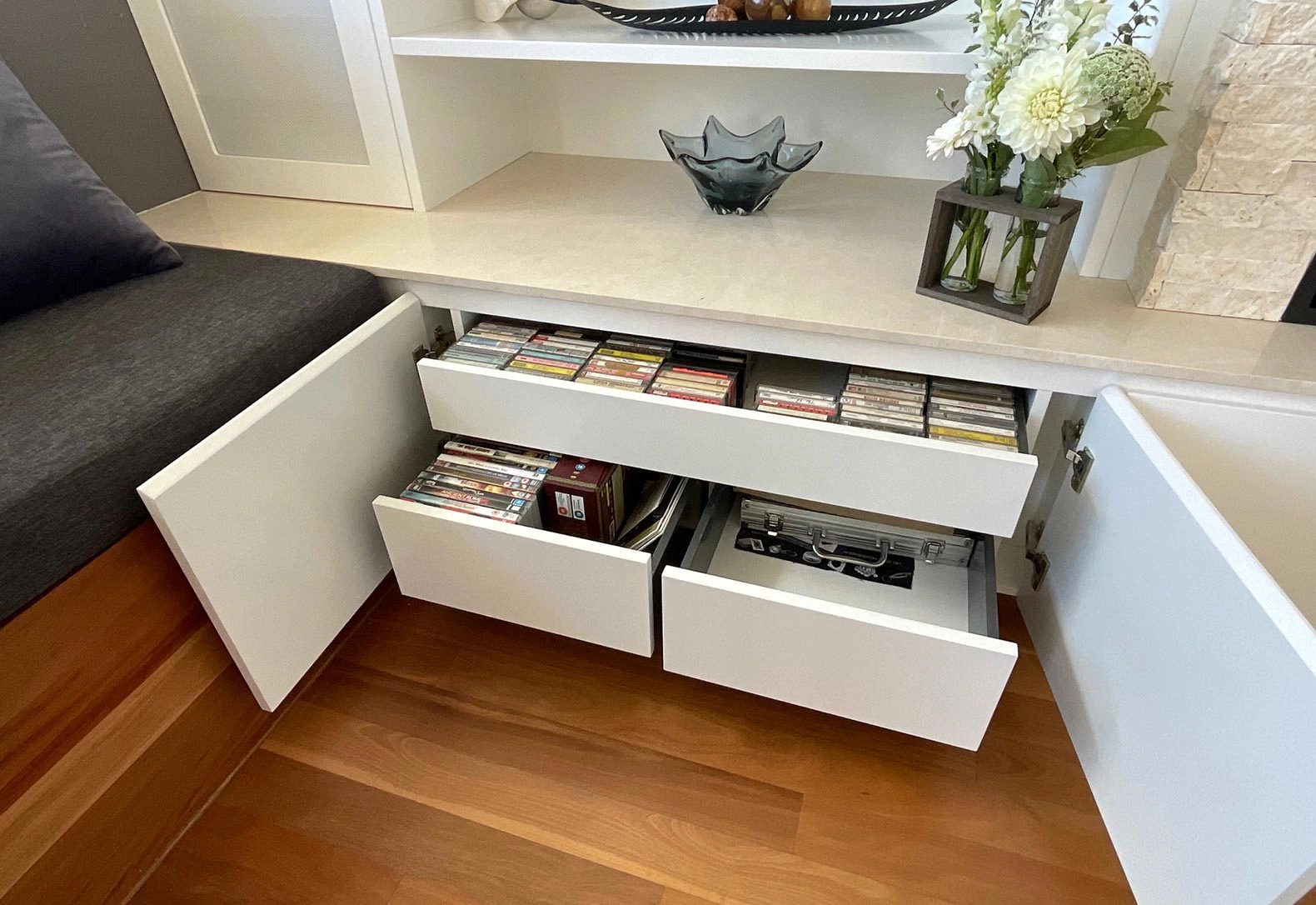 A small white cabinet with drawers beside a cozy couch in a well-decorated living space