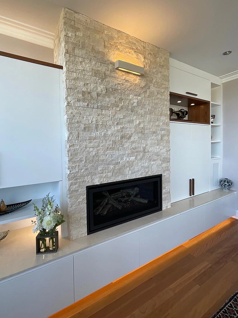 A contemporary living room featuring a stylish stone fireplace as the focal point, surrounded by elegant furnishings