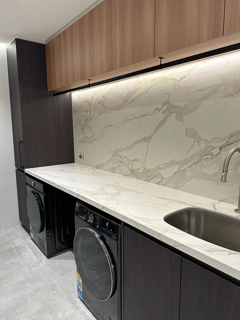 Stylish kitchen with polished marble countertops and a washer and dryer, blending aesthetics with practicality