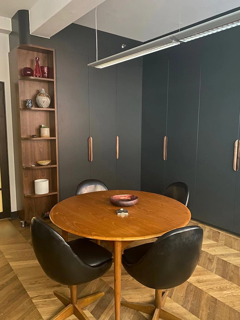 A conference table surrounded by chairs in a room featuring sleek black walls