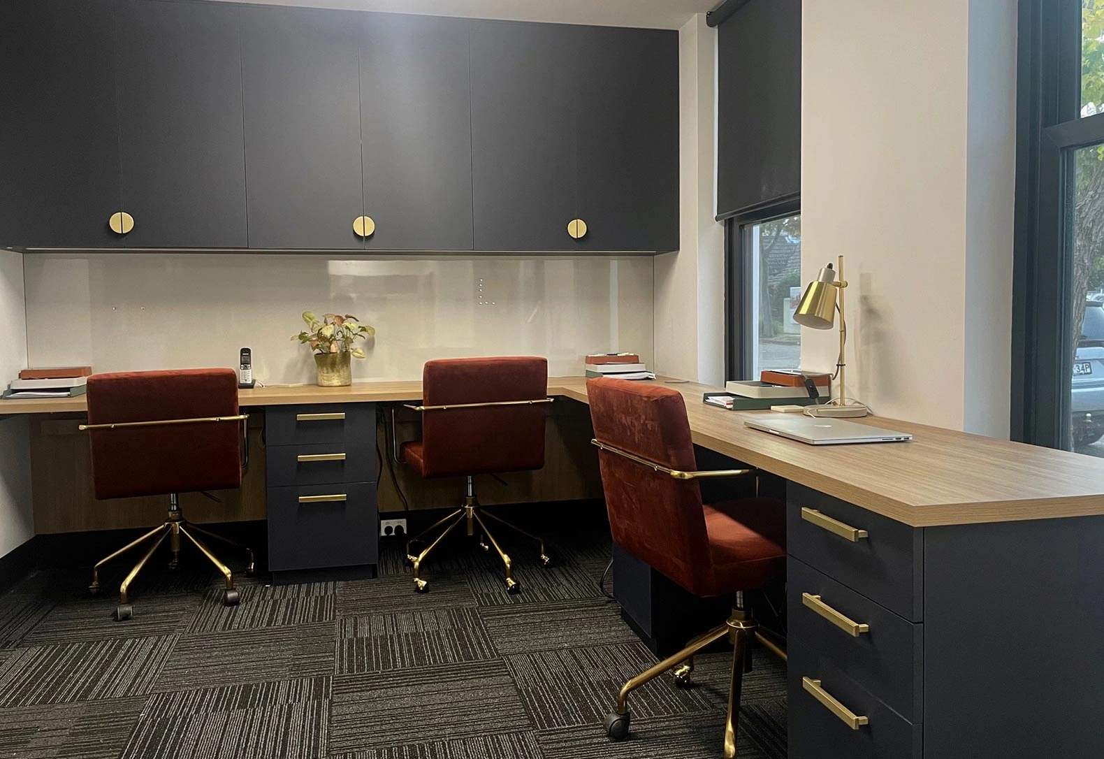 A clean and organized office with two desks placed by a window, enhancing the workspace with natural light