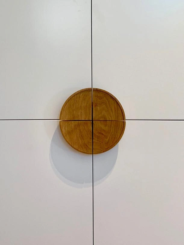 A wooden bowl rests against a white wall