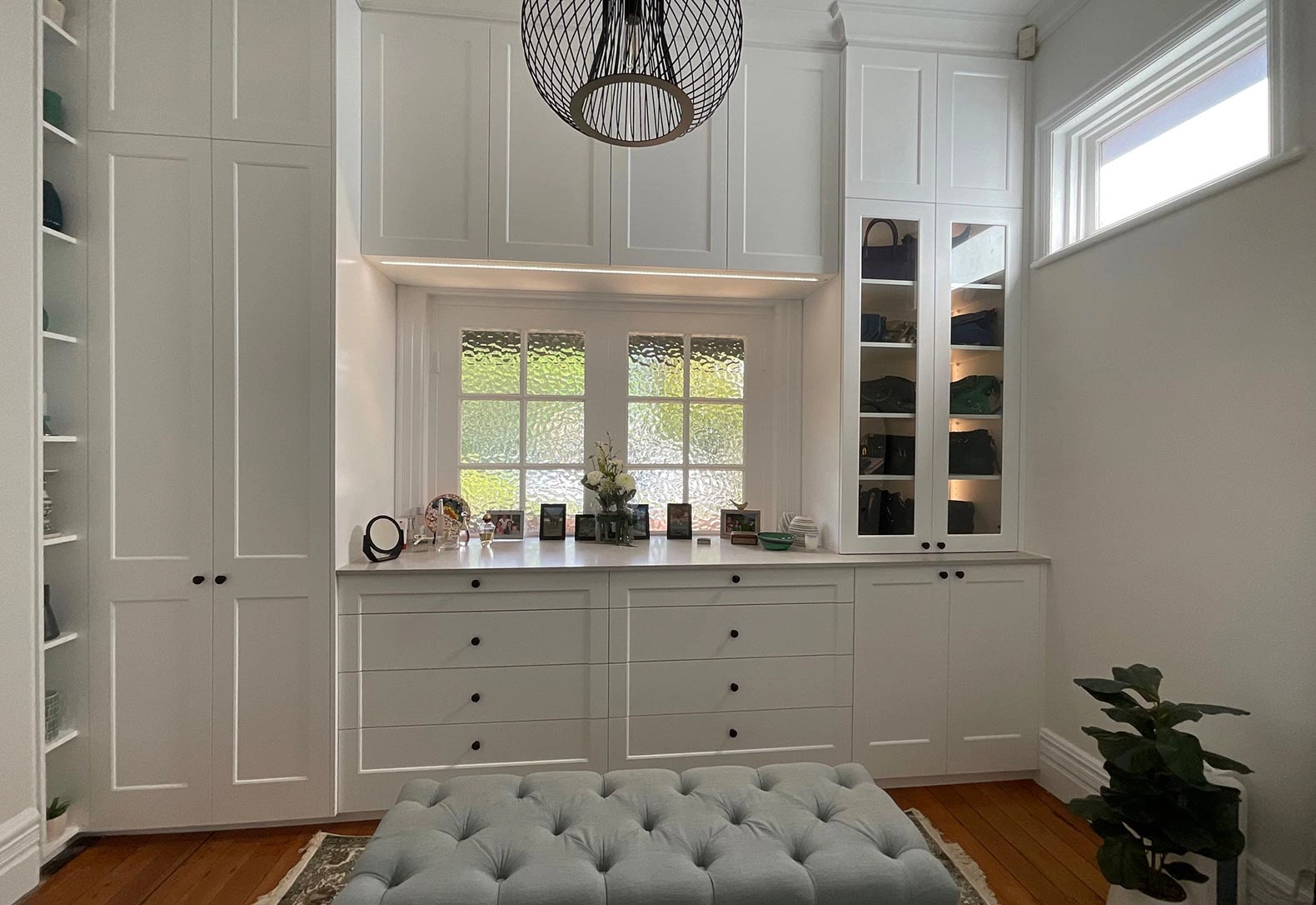 Spacious white room showcasing elegant white cabinets and a simple bench