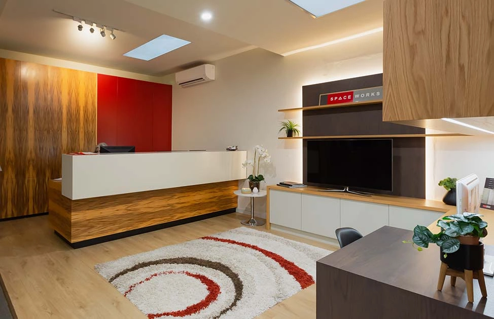 Stylish modern office highlighted by a striking red accent wall, complete with contemporary furniture and ample natural light