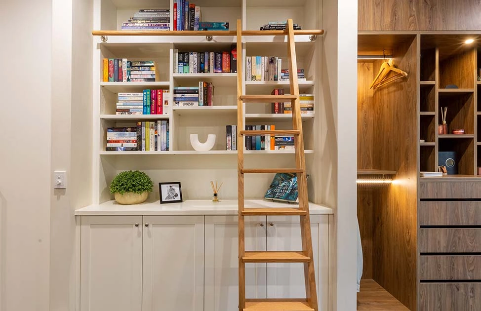 Stylish bookcase stacked with various books, accompanied by a ladder for reaching the higher shelves effortlessly