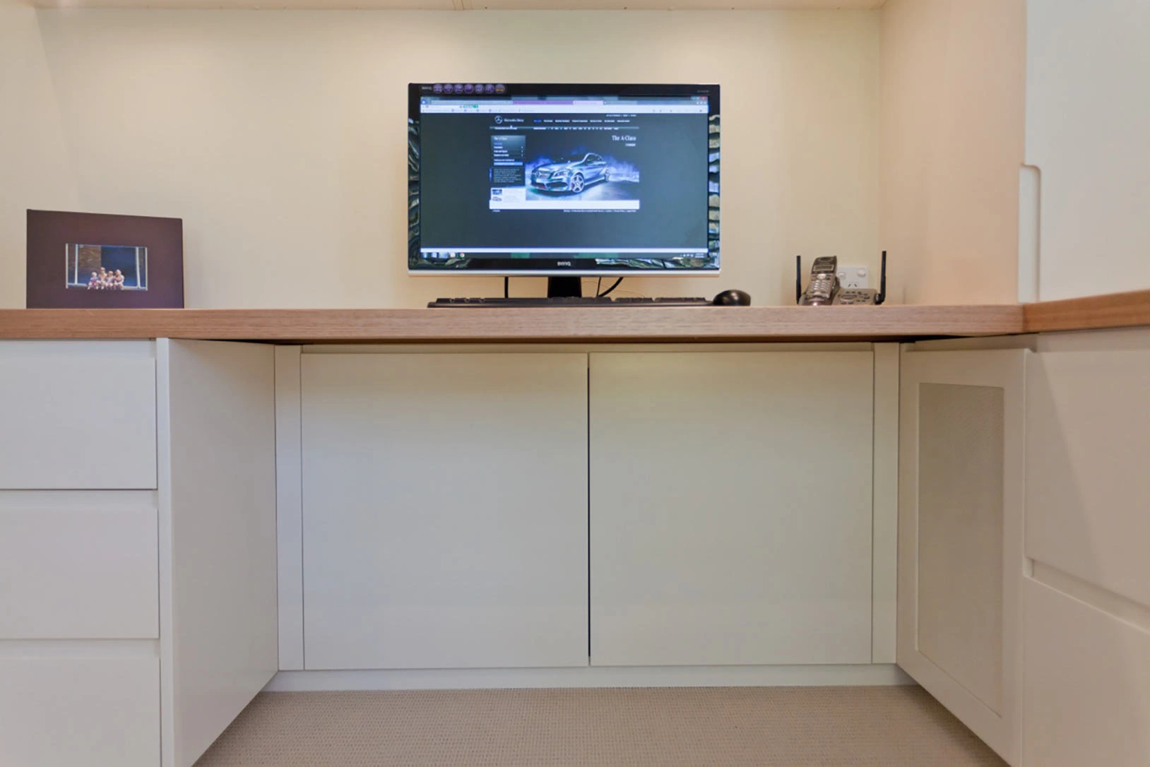 A small room featuring a desk with a computer monitor