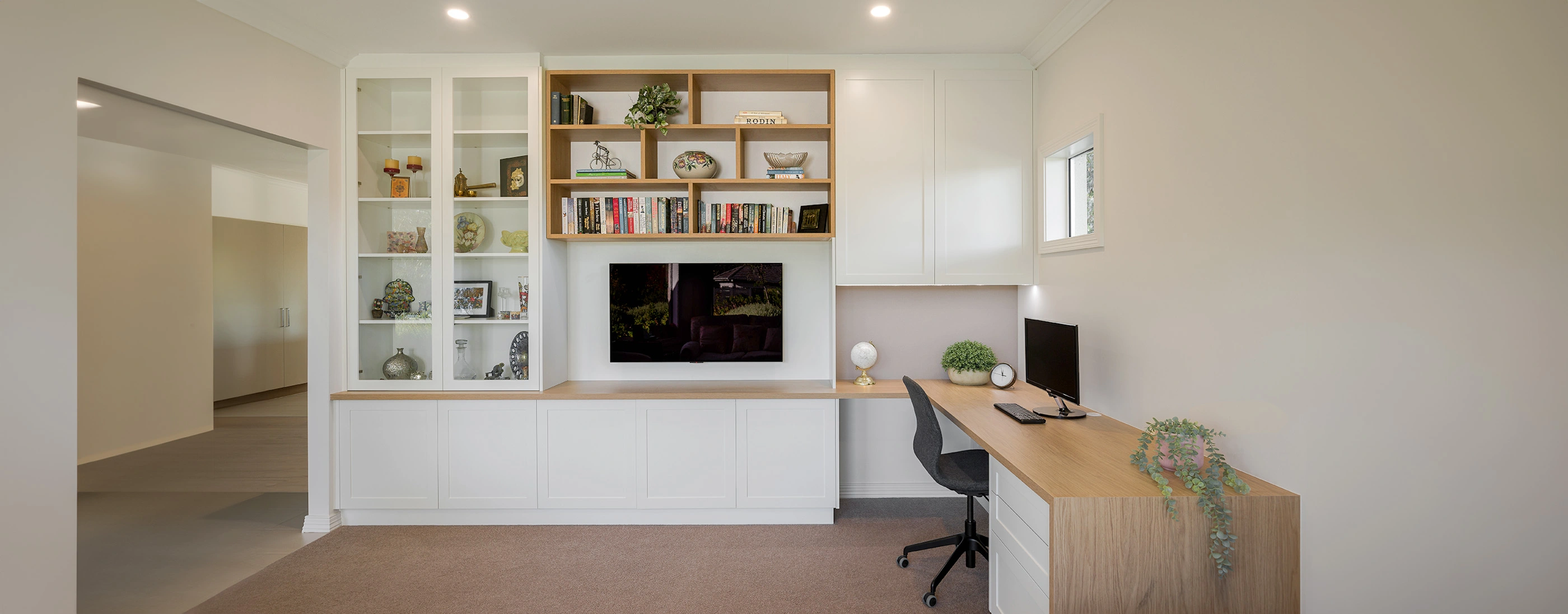 A well-organized home office featuring a desk, a bookshelf filled with books, and a bright window