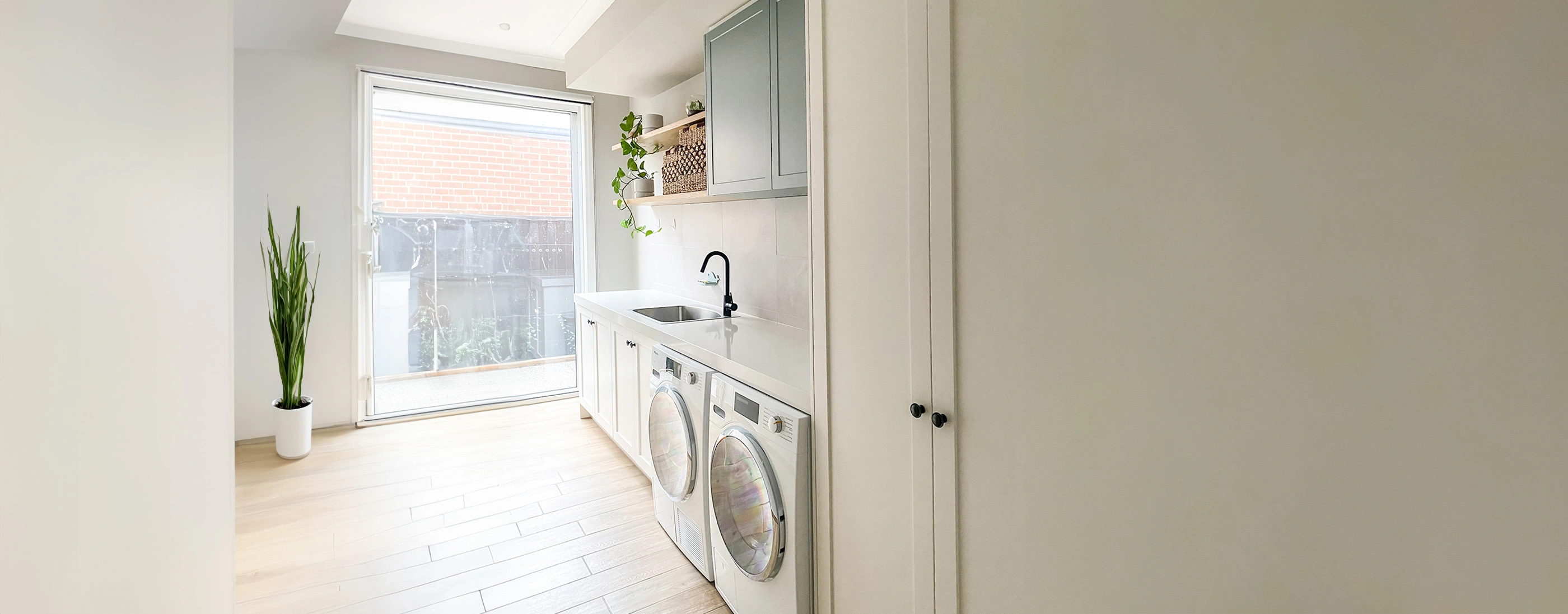 Spacious laundry room equipped with a washer and dryer, surrounded by shelves filled with laundry supplies and bright decor