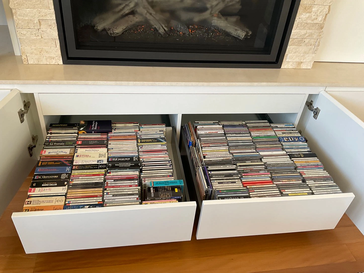 A white cabinet containing two drawers, each filled with various CDs arranged for easy access