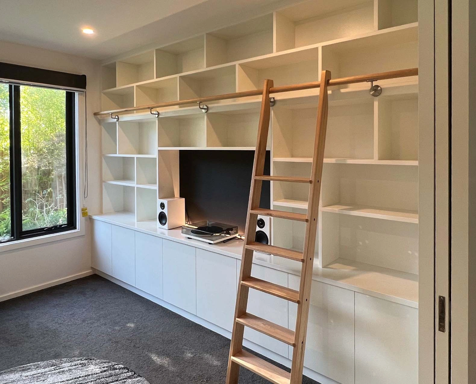 A ladder positioned in front of a white bookcase, showcasing a clean and organized interior space