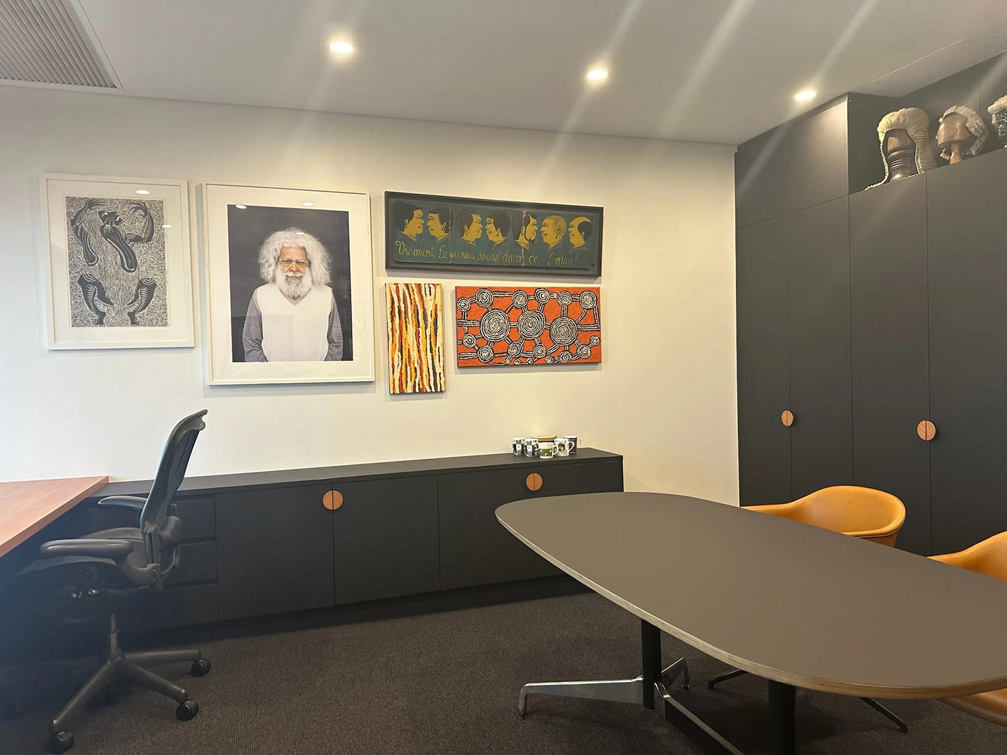 A well-organized office space with a desk, comfortable chairs, and decorative pictures displayed on the walls