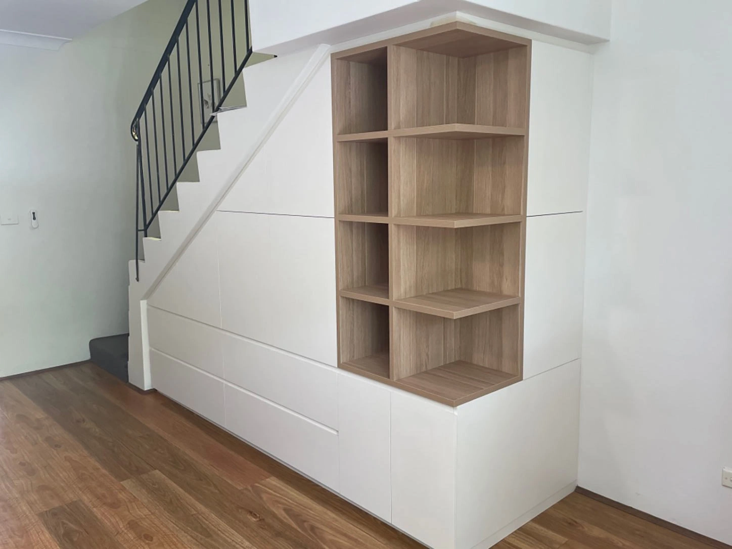 White wall complemented by a bookcase and stairs