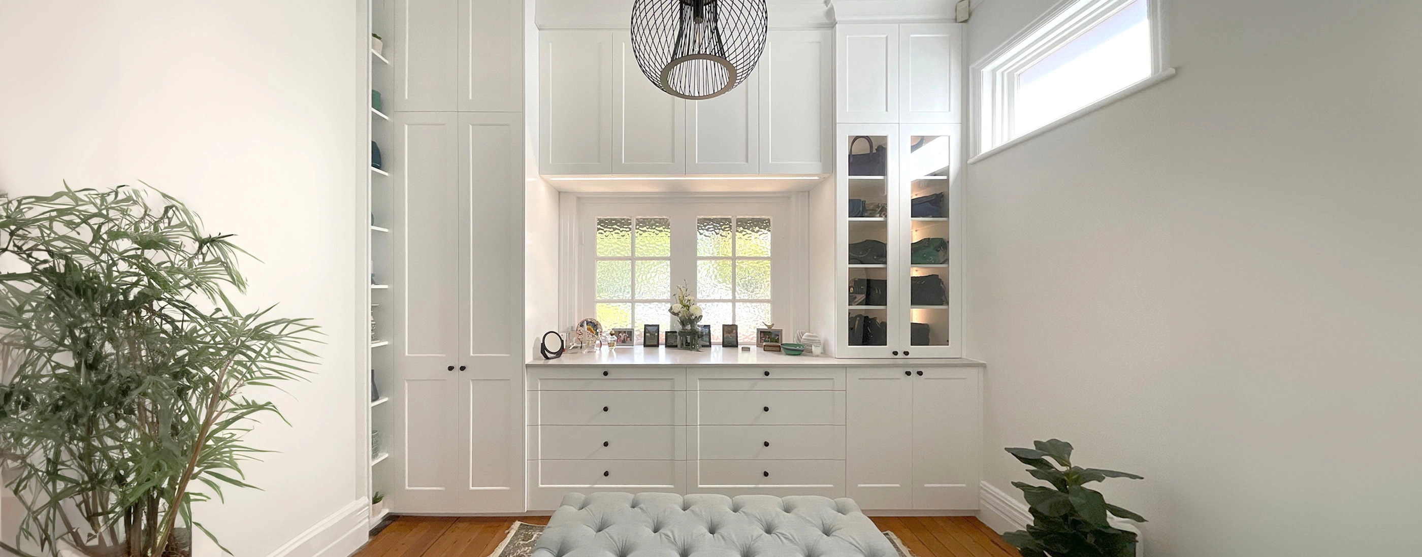 Spacious white hallway with a minimalist bench and a decorative potted plant